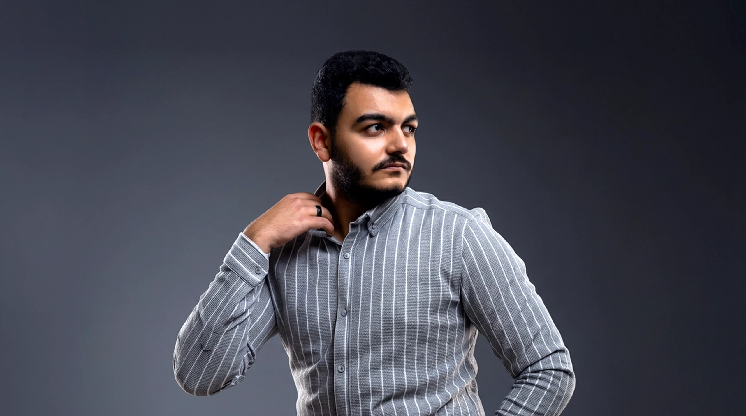 Studio portrait of Ahmed ElKilany in a grey striped shirt